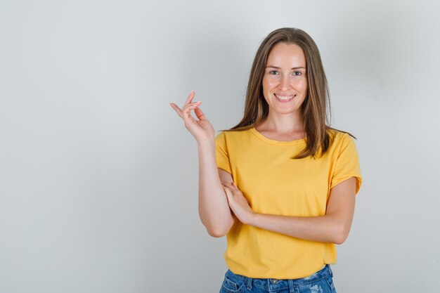 Mujer joven sonriendo y apuntando lejos en camiseta