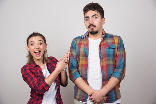 Mujer joven sonriendo y señalando al hombre ofendido.