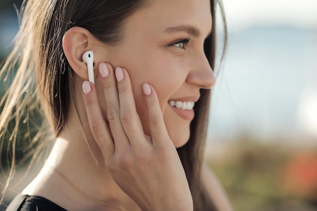 mujer joven sonriente con auriculares al aire libre
