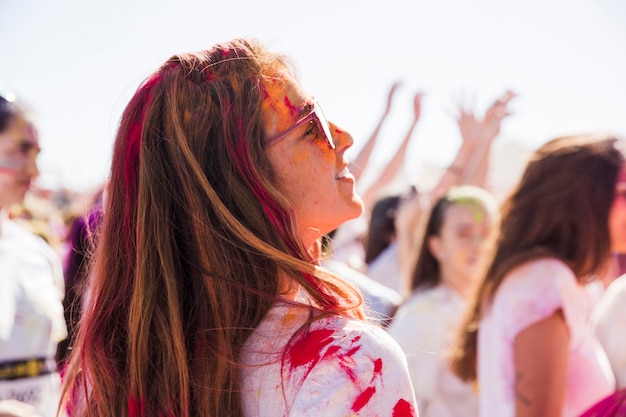 Mujer joven sonriente con el color del holi que mira lejos