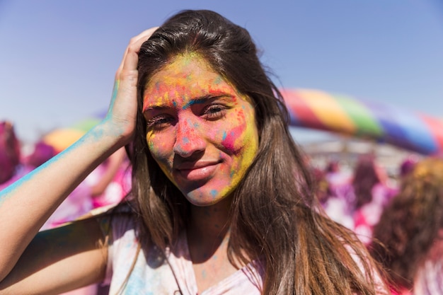 Foto gratuita la mujer joven sonriente cubrió su cara con color del holi