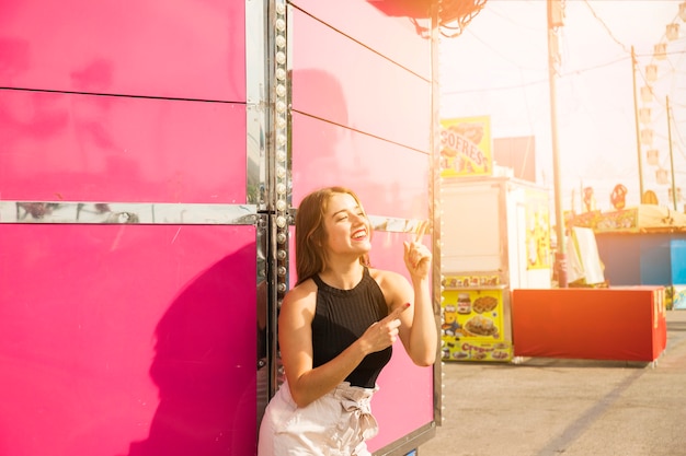 Mujer joven sonriente elegante en el parque de atracciones