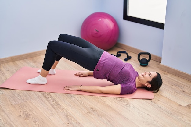 Mujer joven sonriente entrenamiento abs ejercicio seguro en el centro deportivo