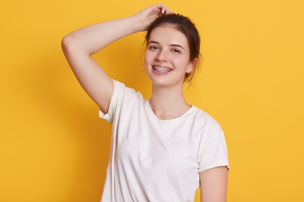 Mujer joven sonriente con expresión facial feliz, vistiendo camiseta blanca