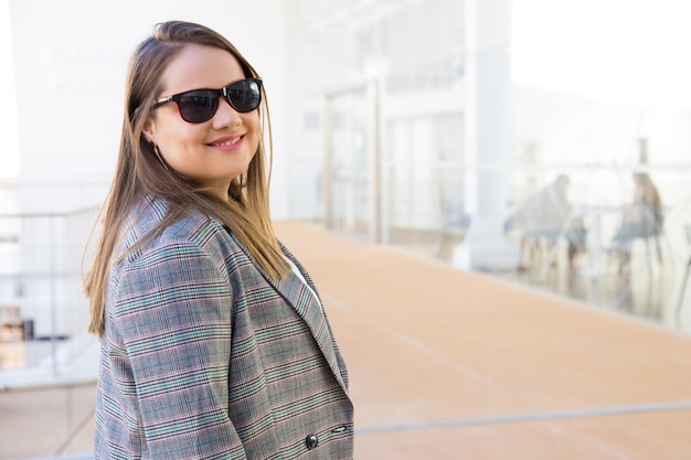 Foto gratuita mujer joven sonriente en gafas de sol mirando a cámara