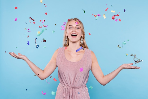 Mujer joven sonriente lanzando confeti