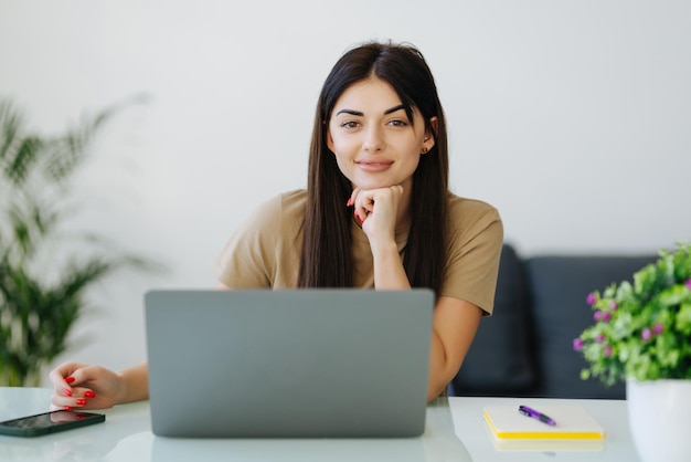 Mujer joven sonriente con laptop en la oficina en casa