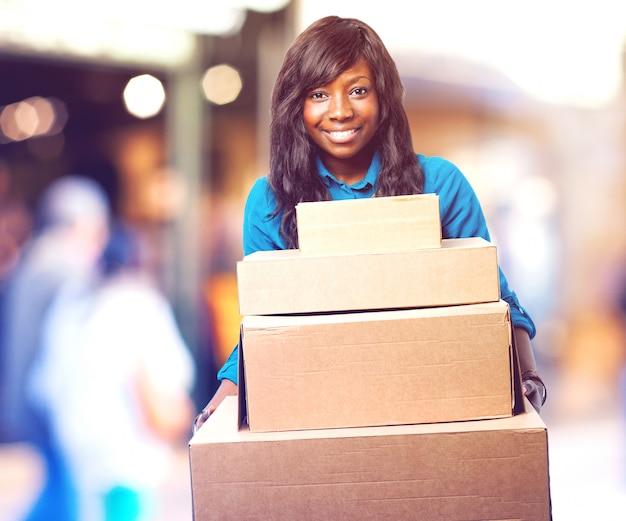 Foto gratuita mujer joven sonriente llevando unas cajas