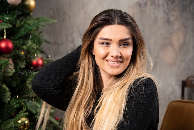 Mujer joven sonriente mirando a otro lado en el acogedor interior de Navidad. Foto de alta calidad