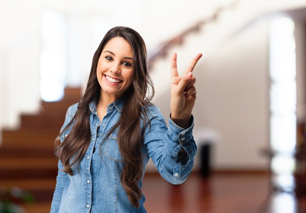 Mujer joven sonriente mostrando el gesto de la victoria