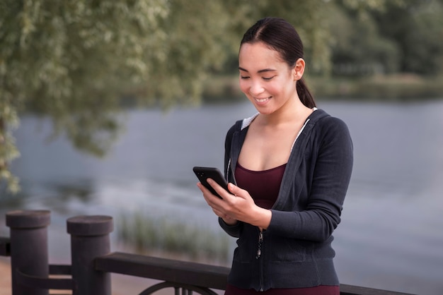 Foto gratuita mujer joven sonriente navegando por teléfono móvil