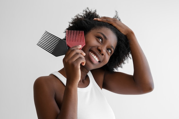 Mujer joven sonriente peinando el cabello tiro medio