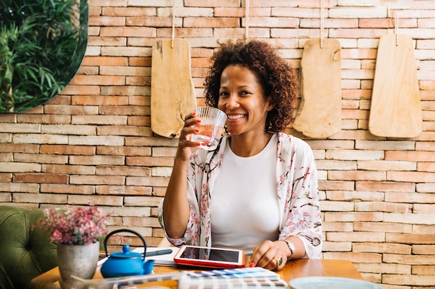 Mujer joven sonriente que bebe el vidrio de jugo