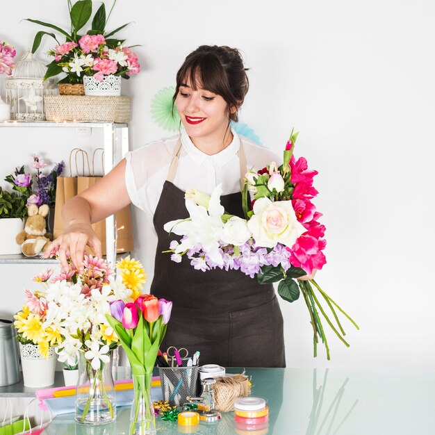 Mujer joven sonriente que clasifica las flores en tienda floral