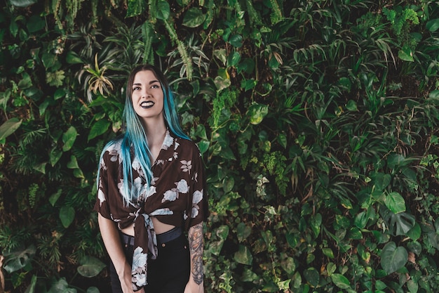 Mujer joven sonriente que se coloca delante de la planta