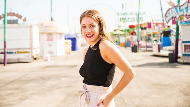 Mujer joven sonriente que se coloca en parque de atracciones