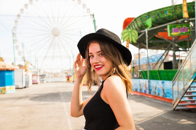 Mujer joven sonriente que goza en el parque de atracciones