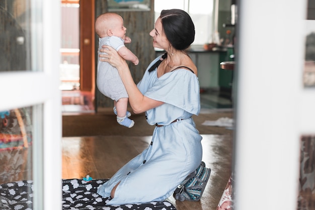 Foto gratuita mujer joven sonriente que juega con su bebé en casa