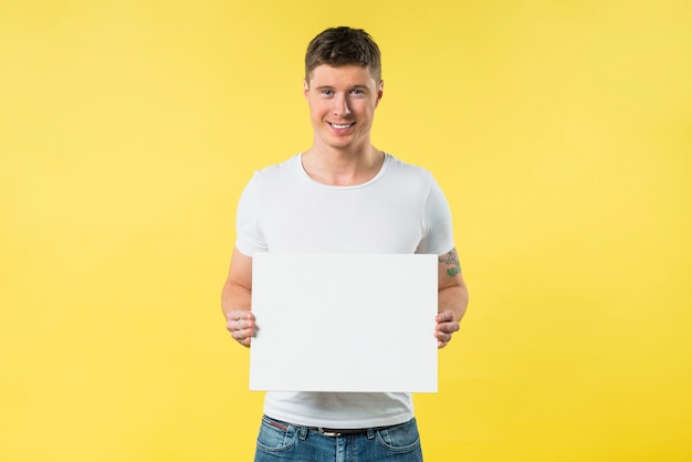 Foto gratuita mujer joven sonriente que muestra el cartel en blanco contra el contexto amarillo