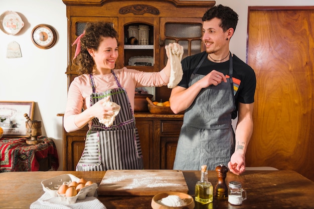 Foto gratuita mujer joven sonriente que muestra la pasta amasada a su marido