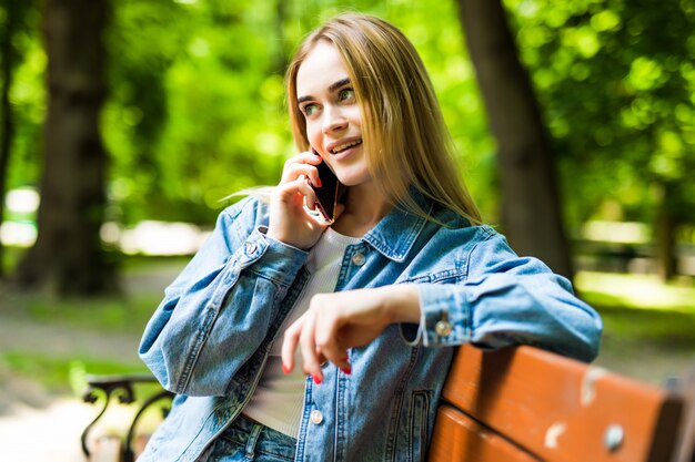 Mujer joven sonriente que pide smartphone en la calle de la ciudad