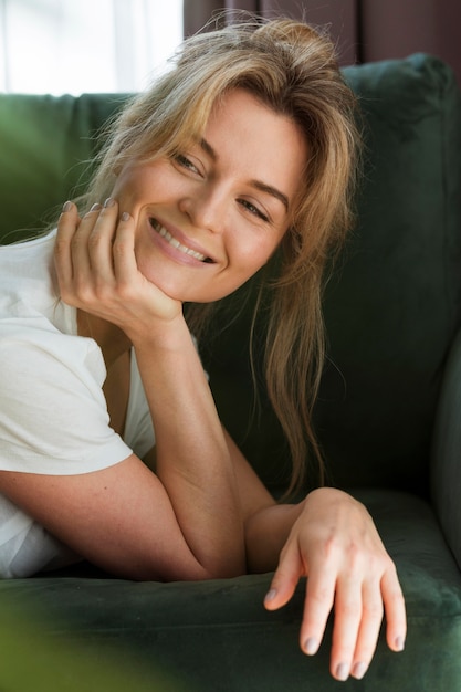 Mujer joven sonriente que se relaja en casa