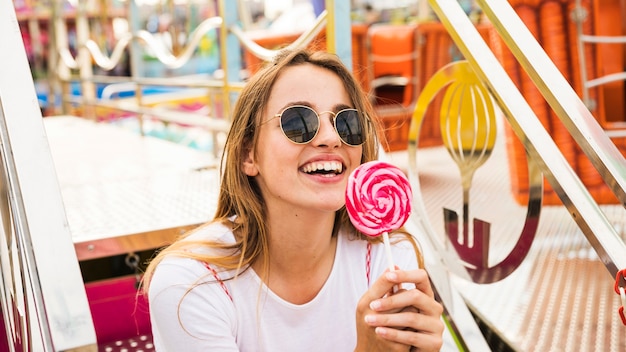 Mujer joven sonriente que sostiene el lollipop rojo y rosado disponible
