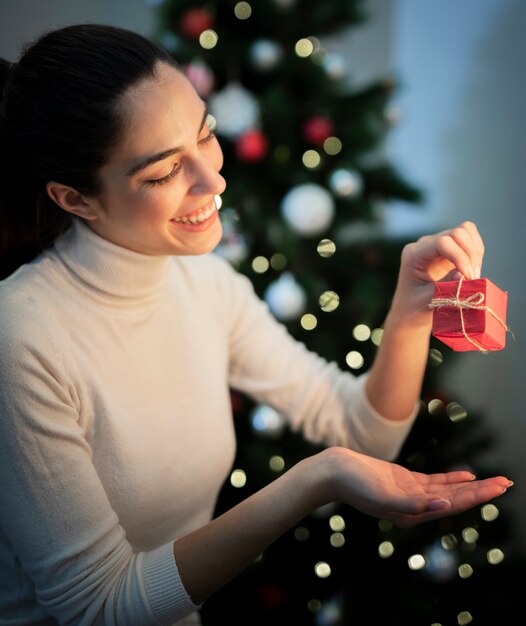 Mujer joven sonriente que sostiene el pequeño regalo