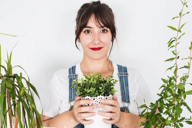 Mujer joven sonriente que sostiene la planta en conserva