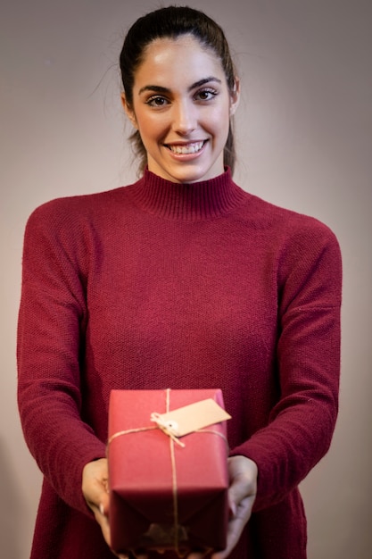 Foto gratuita mujer joven sonriente que sostiene el regalo de la navidad