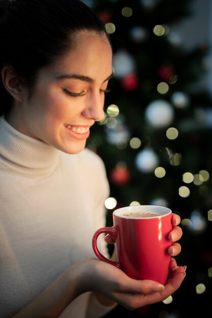 Mujer joven sonriente que sostiene la taza con té