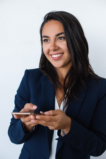 Mujer joven sonriente que sostiene el teléfono móvil