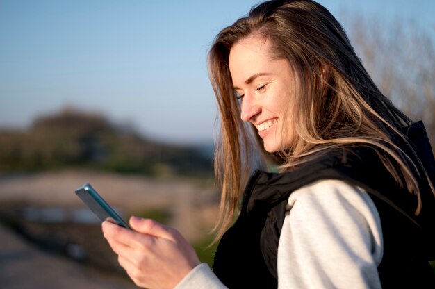 Mujer joven sonriente que usa su teléfono