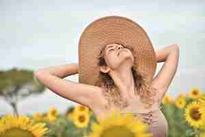 Foto gratuita mujer joven sonriente con sombrero en el campo de girasol - el concepto de felicidad