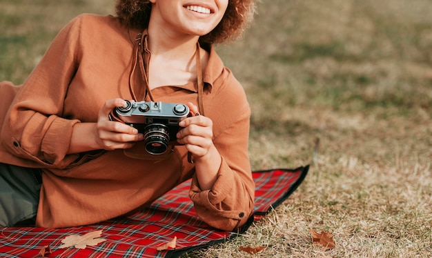 Mujer joven sonriente sosteniendo una cámara con espacio de copia