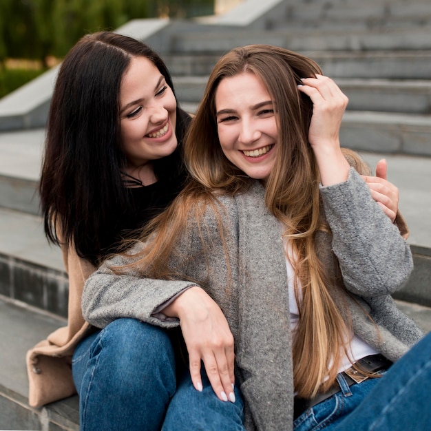 Mujer joven sonriente sosteniendo a su amiga