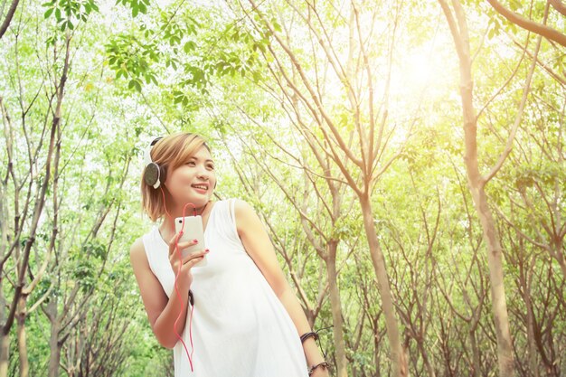 Mujer joven sonriente sujetando su móvil al aire libre