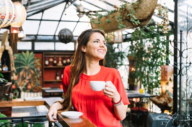 Mujer joven sonriente con la taza de café en caf�