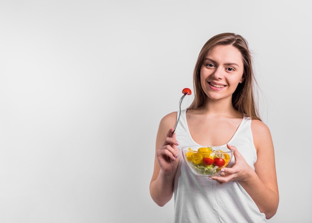 Mujer joven sonriente con el tazón de fuente de ensalada