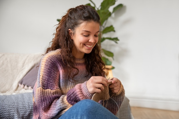 Foto gratuita mujer joven sonriente de tiro medio tejiendo