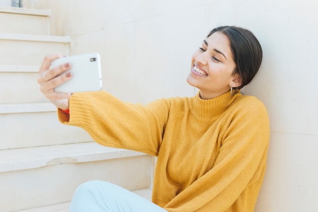 Mujer joven sonriente tomando selfie en teléfono móvil