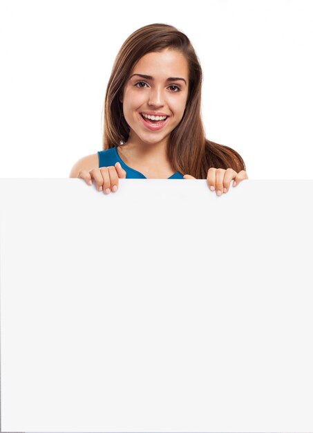 Mujer joven con una sonrisa bonita posando con un cartel vacío