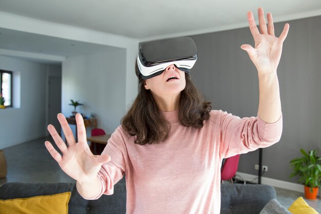 Mujer joven sorprendida que aprende el mundo en auriculares de realidad virtual