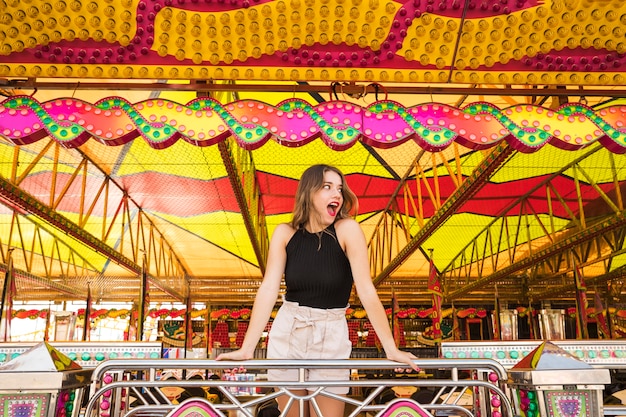 Mujer joven sorprendida que se coloca debajo de la tienda adornada en el parque de atracciones