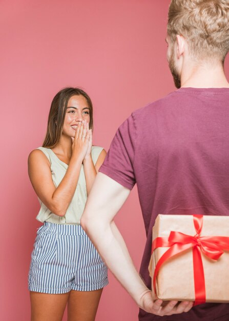 Mujer joven sorprendida que mira su caja de regalo de ocultación del novio