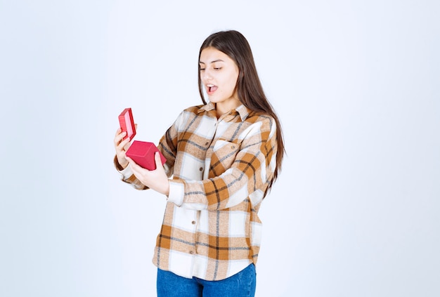 mujer joven sorprendida de regalo sobre pared blanca.