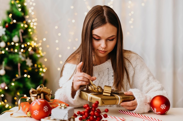 Foto gratuita mujer joven sosteniendo un árbol de navidad en el interior