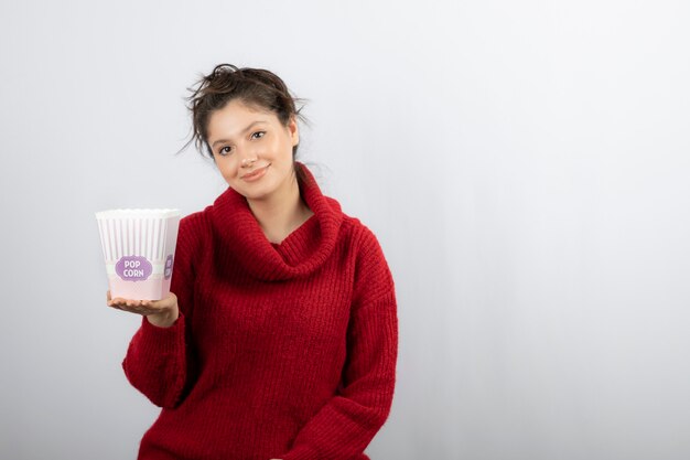 Una mujer joven sosteniendo un balde de palomitas de maíz.