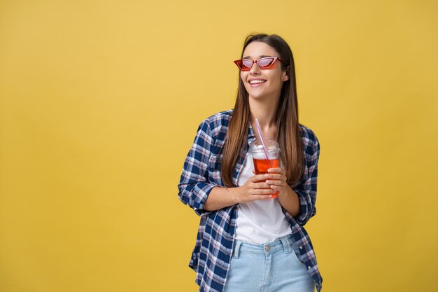 Mujer joven sosteniendo y bebiendo bebidas frías en ropa casual chica guapa sonriendo feliz riendo mirando a la cámara