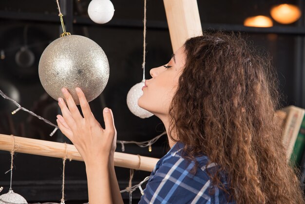 Mujer joven sosteniendo una bola de Navidad dorada